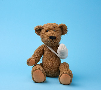 棕色的棕色卷发泰迪熊 用白色的双脚抚摸疾病孩子婴儿石膏伤害娃娃创伤蓝色乐趣病人图片