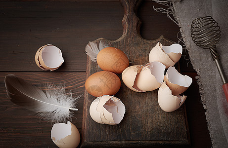 褐色生鸡蛋 贝壳 切割板和手持木板乡村厨房农场烹饪美食食物木头金属母鸡图片