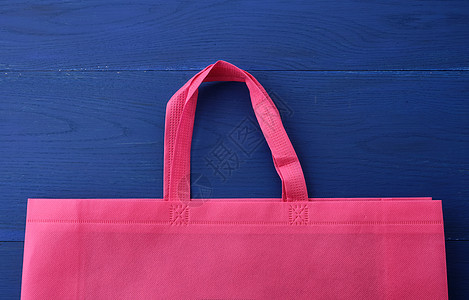 蓝色木质背景上可重复使用的粉色粘胶袋手提包生态材料零售织物木板环境粘胶回收纺织品图片