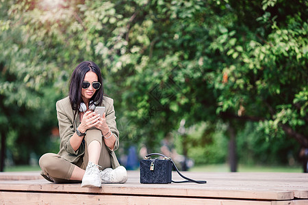 可爱的女人坐在公园里时正在用手机读短信 这很可爱时间女士女性智能概念娱乐电话5g应用程序女孩图片