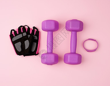 一对紫色塑料哑铃和 粉红色背面的黑色手套图片