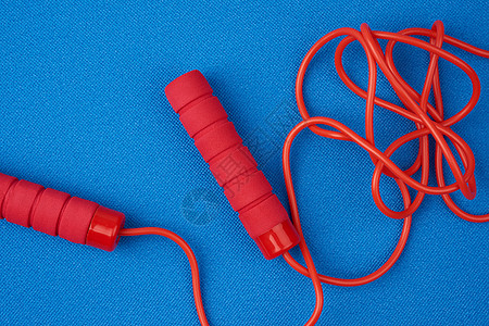红色的跳绳在新青蓝运动垫子上活动健身房塑料蓝色力量工具曲线童年闲暇训练图片