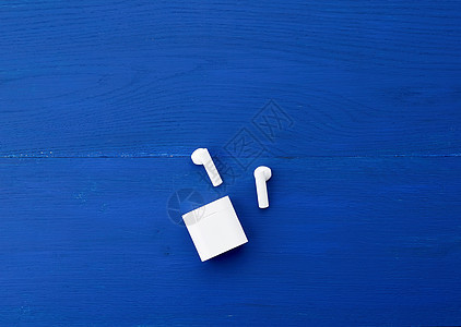 白色无线耳机和蓝木背面的充电箱图片