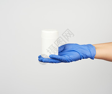 蓝色无菌手套上戴着白塑料罐头和药丸图片