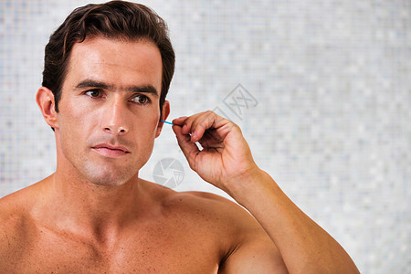 在浴室用棉花芽擦耳朵的年轻有吸引力的男人的肖像 洗手间图片