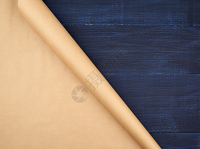 蓝色木质背景上未扭曲的棕色牛皮纸卷床单折叠文档木头材料滚动包装回收木板生态图片