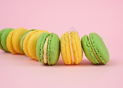 粉红背景的绿色和黄黄色圆圆烤面纱味道营养杏仁小吃奶油糖果食物甜点面包酥皮图片