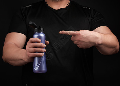 肌肉有肌肉的成年男性运动员持有塑料水瓶液体运动装工作室男人饮料瓶子健康黑色身体食物图片