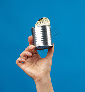 女性手在蓝色背景上可以使用金属圆铁罐食物养护装罐产品广告营养贮存圆柱罐头商品图片