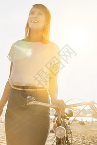 在海滩上行走时骑自行车的年轻有吸引力的女商务人士的肖像女性活动工作微笑团队畅销书下载商务寒意建设图片