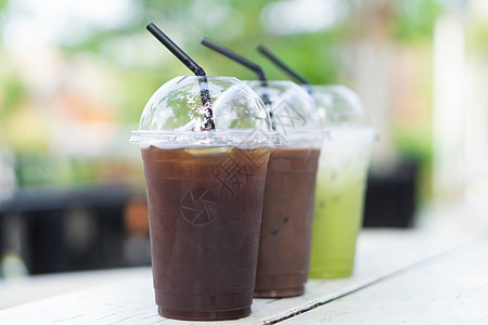 闭紧冰杯 绿色茶叶和木塔上的冰咖啡冰镇茶点杯子饮料食物牛奶咖啡店玻璃桌子稻草图片