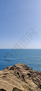从岩石灰尘悬崖上直观蓝色海洋的垂直景观图片