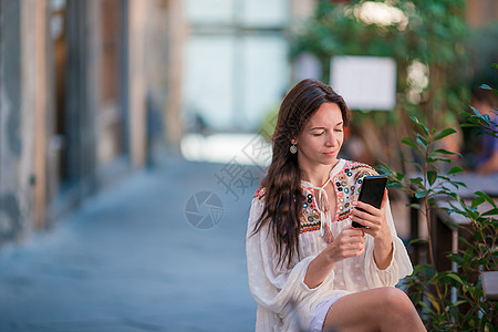 坐在户外咖啡馆喝咖啡 使用智能手机的美丽女子肖像 笑声喜悦杯子卫生饮料女孩快乐味道黑发餐厅治疗图片