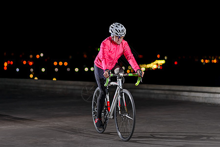 健康生活方式和城市体育概念 在城市夜间骑行公路自行车的女赛事妇女运动员图片