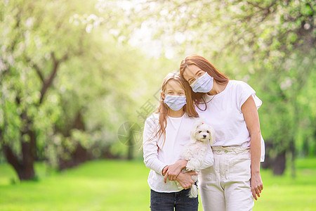母亲和女儿家庭在盛开的樱花花园中戴面罩图片