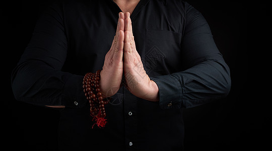 穿黑衬衣的男子展示了Namaste祈祷泥土图片