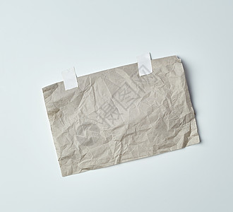 用白色胶带粘上的灰色皱巴巴的纸海报框架皱纹胶水工作室床单邮政广告传单磁带背景图片