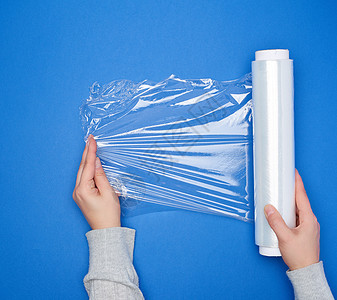 手握着一卷大卷伤口的白色透明薄膜 用于包装空白塑料管子电影女性磁带工业蓝色工作室圆形图片