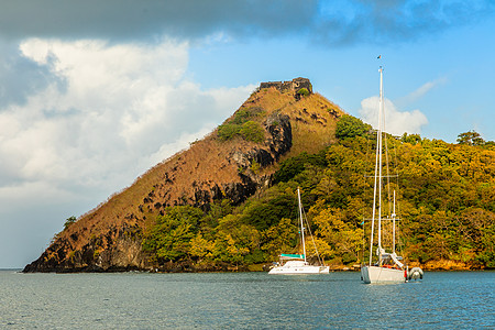 游艇停靠在鸽子岛上 岩石上有堡垒废墟旅行海洋海景热带鸽子风景天空公园爬坡历史性图片