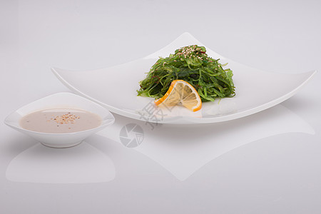 白盘中的沙拉正方形白色芝麻叶子反射食物绿色柠檬海藻图片