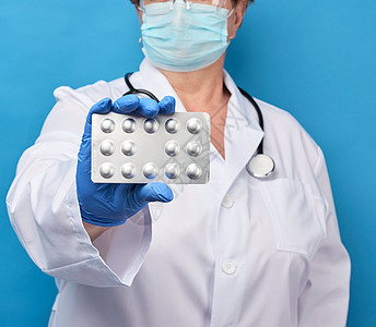 穿白大衣和蓝色乳胶手套的女医务人员持有一包药品抗生素疾病止痛药医院女性职业药剂师药物药片图片