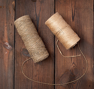 棕色线拧成木制背景上的线轴材料缝纫细绳纤维回收黄麻工艺纺织品卷轴筒管图片