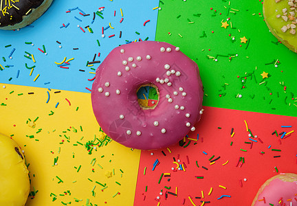 圆形甜甜甜圈 在明亮的多彩色上喷洒巧克力磨砂奶油小雨圆圈甜点小吃蛋糕面包面团图片