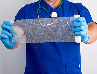 穿蓝色制服和乳胶手套的医生持有一卷白面包包援助男性药品男人外科医院病人疾病治疗诊所图片