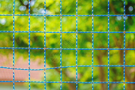 具有绿色自然模糊背景的钢丝网栅栏图片