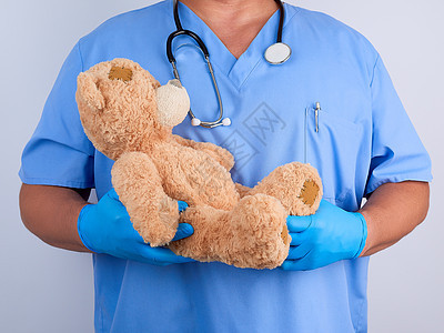 穿蓝色制服和白乳胶手套的医生 戴棕色衣帽治疗成人从业者儿科职业男人帮助康复疾病动物图片