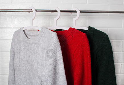 瓷砖衣服挂在衣架上 穿红色 绿色和黑兰格的羊毛衣湿气零售织物针织品外套壁橱运动衫羊毛球衣衬衫背景