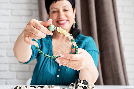 美丽的笑着微笑的中年妇女 欣赏珠宝项链金子手镯奢华珠子首饰爱好编织艺术珍珠艺术家图片