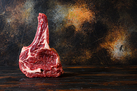 Raw Cowboy 牛仔牛肉大理石牛排 在肉食的侧边视图中与带有深黑木板的生锈旧切割板相比图片