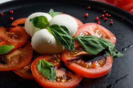 用西红柿 马扎里拉 绿色烤肉加热新鲜意大利沙拉 在白色背景选择性焦点下 紧贴在黑板盘上图片