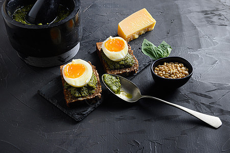 用老旧的生锈木鸡蛋番尼面包和意大利早餐中的青松银勺以及黑石混凝土桌面上的绿色虫害成份所制成的绿虫图片