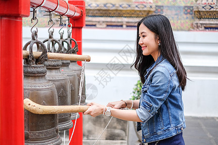 女人在泰国佛教寺庙敲响铃声女士宗教头发钟声戒指学校平底锅顺口溜传统工艺图片