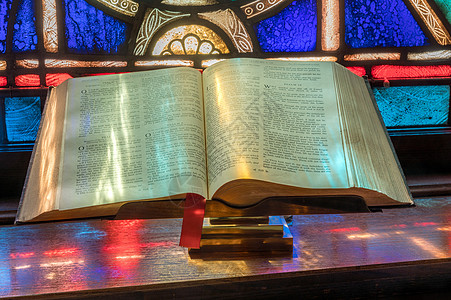 玻璃教堂彩色玻璃窗上的灯光在美国教堂的 开放圣经 上落下历史辉光窗户建筑学横梁教会反射射线信仰崇拜背景
