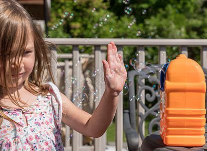 Childs 机械肥皂泡沫制造机或吹风机 前面有女孩圆圈孩子火花喜悦乐趣制作者玩具肥皂泡空气气泡图片