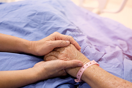 女人的手握着母亲的手 她睡在夫妻皱纹老年女士医院护士毯子管子疾病女性图片
