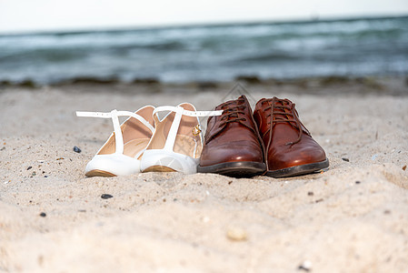 两对女士和绅士 鞋在海滩前的沙滩上背景图片