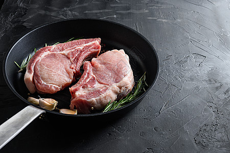 煎锅烤锅中的猪肋排配香草 香料侧视黑石背景空间 用于文本垂直图片