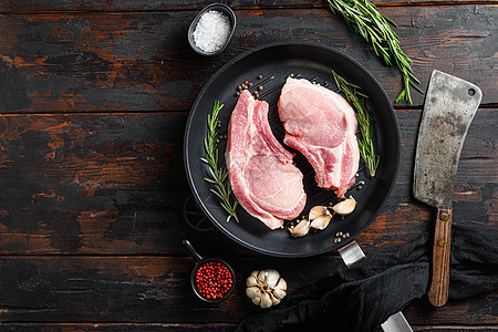 生猪肉排 在铁炉里配有草药和毛巾刀 用于在暗木质表面屠宰和烹饪的食材中切除;具有复制空间的食物背景图片