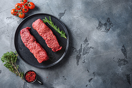 黑色板块上的有机牛排 大理石牛肉和西红柿胡萝卜 在灰石表面背景的顶层文字浏览空间上图片