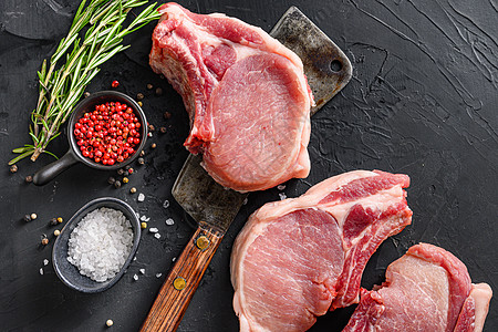 含有草药和香料的生猪肉排 配有美食在黑背景文字空间上的鲜肉刀图片