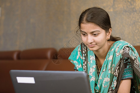 微笑的印度女学生或忙于笔记本电脑的员工穿着休闲服坐在家里 快乐的女性学习 电子学习 使用在线软件或技术应用程序工作 教育理念图片