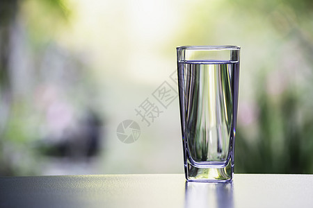 以自然背景在桌边的玻璃杯中的水图片