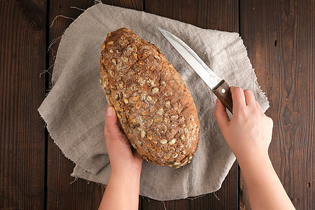 女性手拿着一把刀 在面包面包的烤面包上白色面包师木板黑色产品厨师小麦棕色乡村美食图片