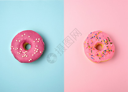 两个整圆粉红色甜甜圈 带有彩色喷洒的花朵 就躺在蓝色上图片