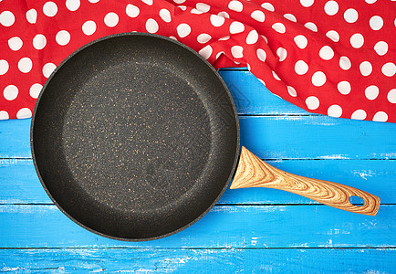 空的黑色圆形不粘煎锅 蓝色木头上有把手桌子棉布风格厨房食物装饰纺织品桌布菜单毛巾图片