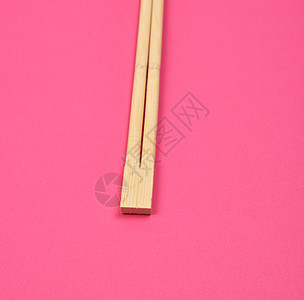 粉红背景的两根木筷子褐色工具竹子用具厨房午餐木头食物粉色传统图片